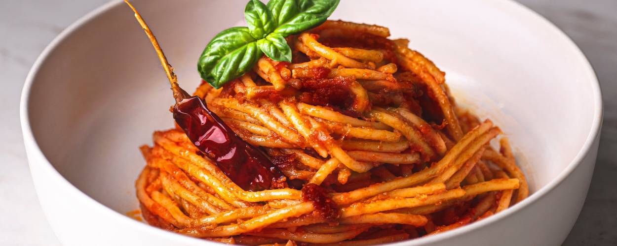 Spaghetti all’assassina in einer weißen Schale, getoppt mit einer getrockneten Chili und Basilikum