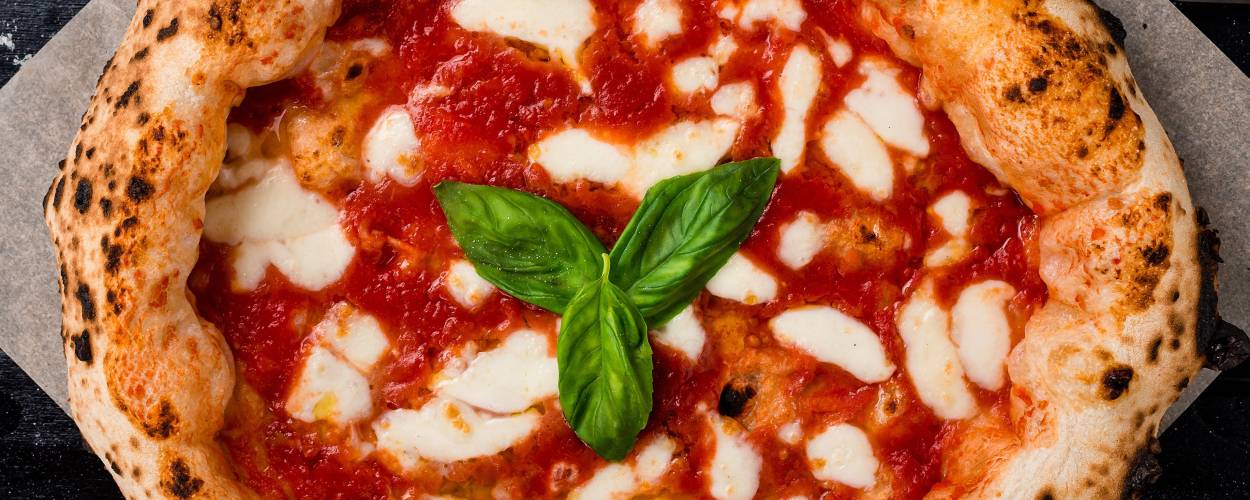 Pizza Napoletana mit Basilikum garniert auf einem Stück Backpapier