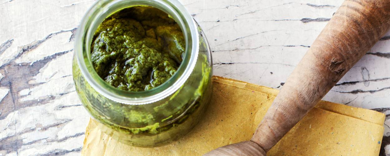 Selbst gemachtes Pistazienpesto in einem Glas, daneben Pistazien auf einem Tisch