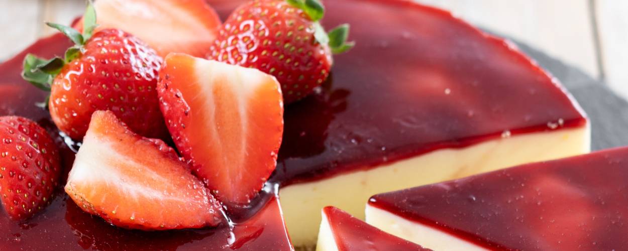 Runder Erdbeer-Panna cotta Cheesecake ohne Backen angeschnitten auf einer Schieferplatte