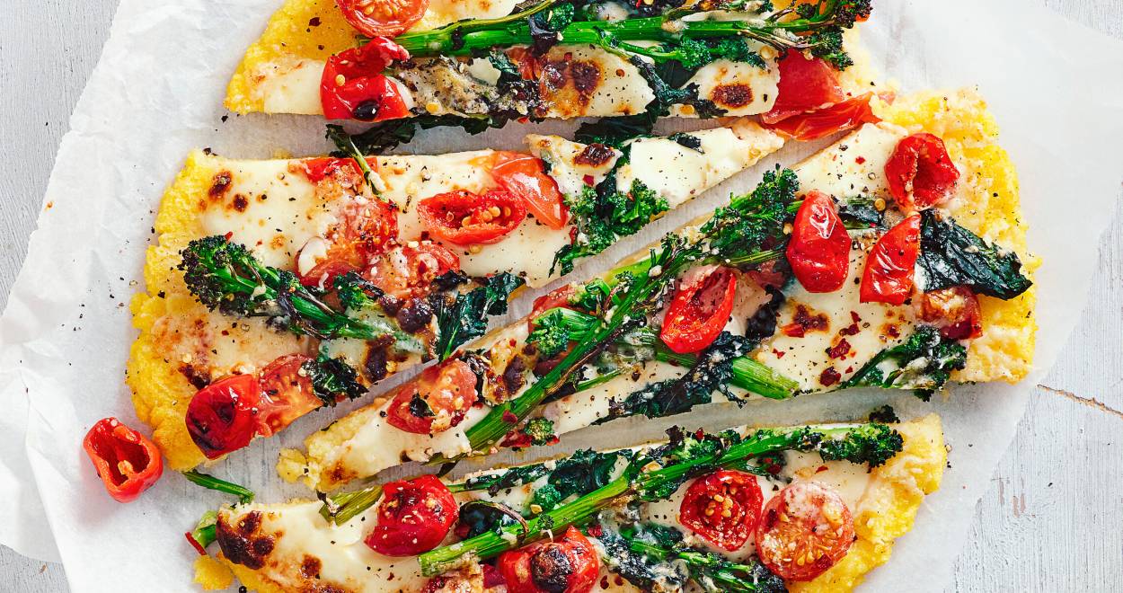 Runde Polentapizza mit Gemüse und Mozzarella in Streifen geschnitten auf einem Teller