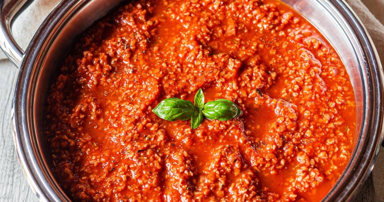 Bolognese Soße in einem Topf garniert mit frischem Basilikum auf einem Küchentisch