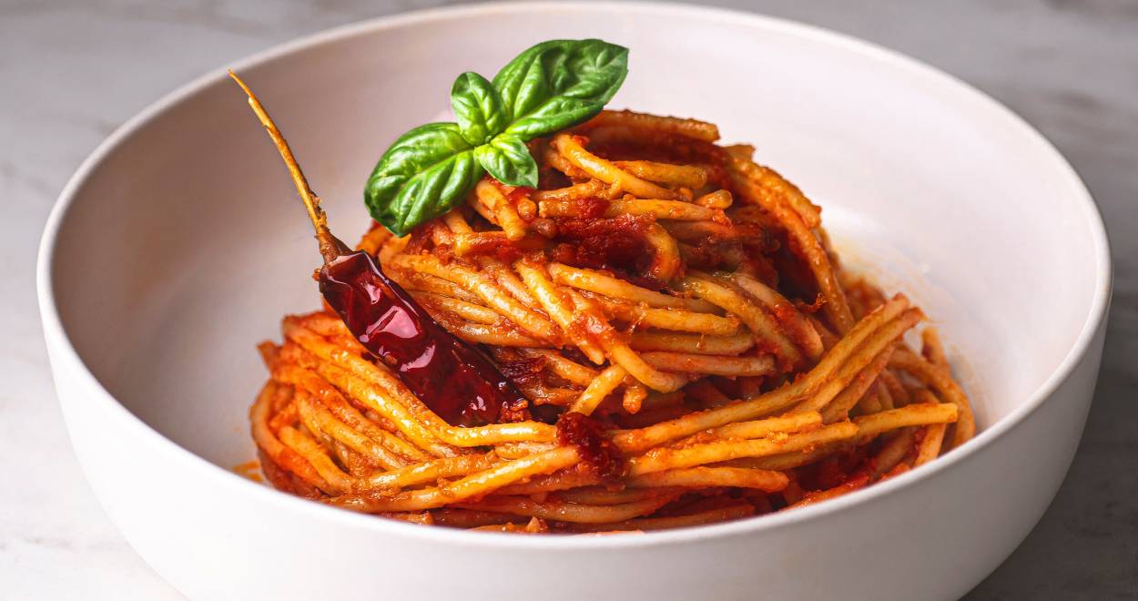 Spaghetti all’assassina in einer weißen Schale, getoppt mit einer getrockneten Chili und Basilikum
