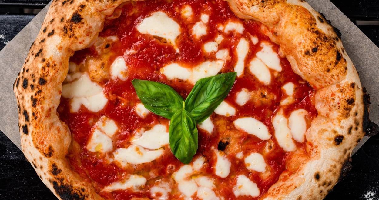 Pizza Napoletana mit Basilikum garniert auf einem Stück Backpapier