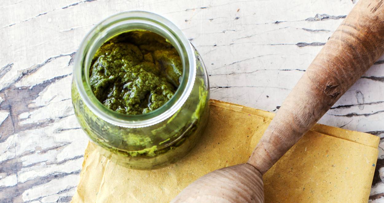 Selbst gemachtes Pistazienpesto in einem Glas, daneben Pistazien auf einem Tisch