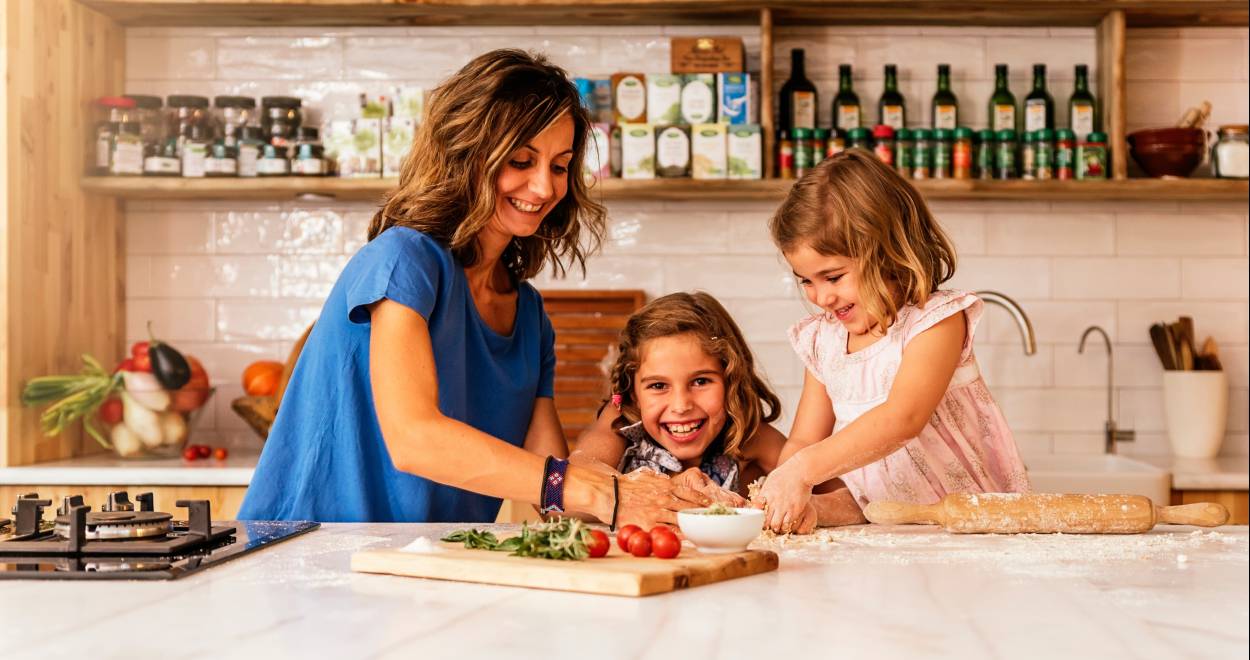 Eine Mutter backt in der Küche Pizza mit ihren zwei Töchtern