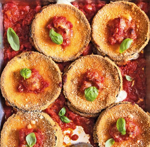 gebackene, panierte Aubergine-Taler mit Caciocavallo-Kruste auf einem Backblech mit Sugo und Basilikumblättern angerichtet