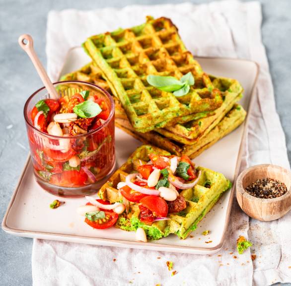 Drei rechteckige Parmesan-Bärlauchwaffeln angerichtet mit Tomatensalat auf einer Servierplatte