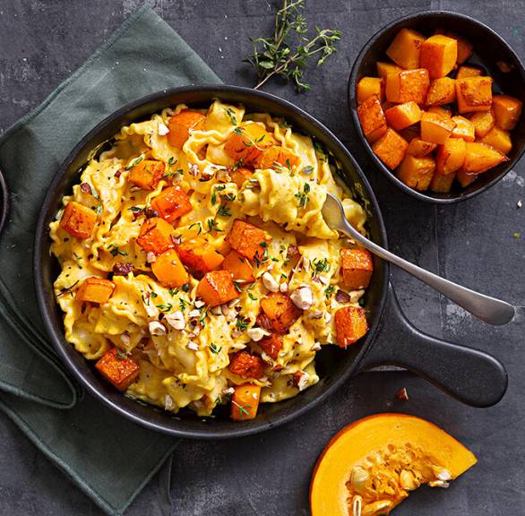 Mafaldine Bandnudeln in einer Pfanne mit Kürbiswürfeln getoppt