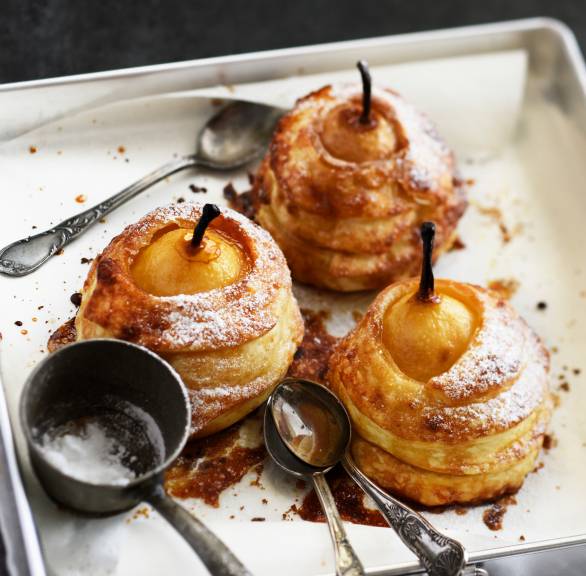 Drei gefüllte Bratbirne im Blätterteigmantel auf einer Servierplatte bestäubt mit Puderzucker