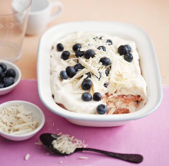 Helles Tiramisu in einer Schale mit Blaubeeren und weißen Schokoladenraspeln getoppt
