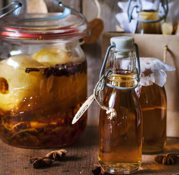 Bratapfellikör in mehrere Flaschen gefüllt, daneben eine weihnachtliche Geschenktüte