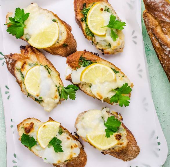 Bruschetta mit Kabeljau, Mozzarella und Zitrone auf einem Tablett garniert mit frischer Petersilie