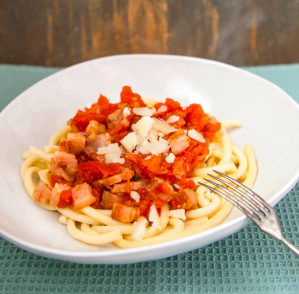 Bucatini-Nudeln in einem tiefen Teller mit Sauce all’amatriciana auf einem Tisch