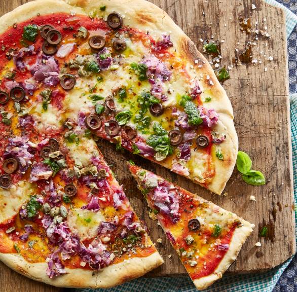 Runde, angeschnittene Zwiebelpizza auf einem Holzbrett