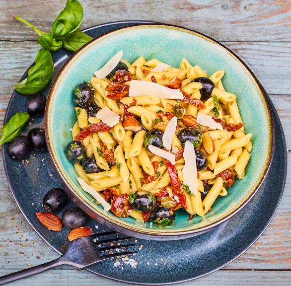 Italienischer Nudelsalat mit Parmesan und Mandeln getoppt in einer Schüssel auf einem Tisch