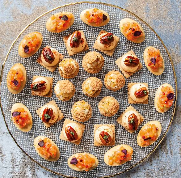 Parmesancracker auf einer runden Platte getoppt mit Kürbiscreme und Pekannüssen