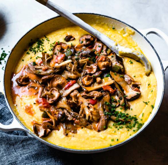 Polenta in einem Topf getoppt mit vielen Pilzen