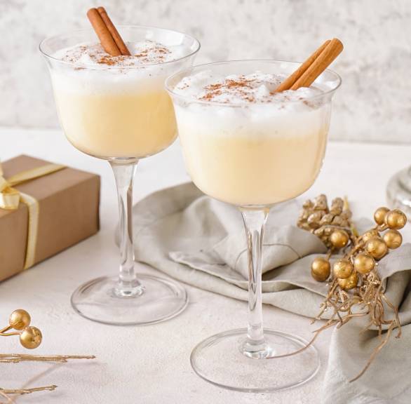 Weihnachtscocktail in zwei Stielgläsern auf einem festlich dekorierten Tisch