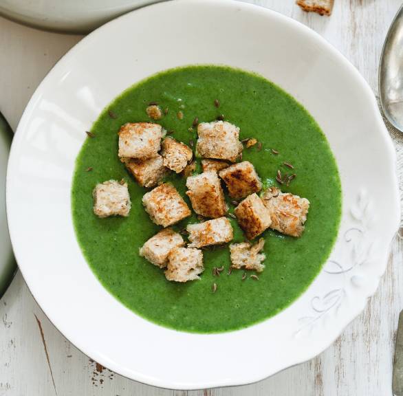 Kartoffel-Spinatsuppe angerichtet auf einem Suppenteller getoppt von selbstgemachten Vollkorn-Croûtons