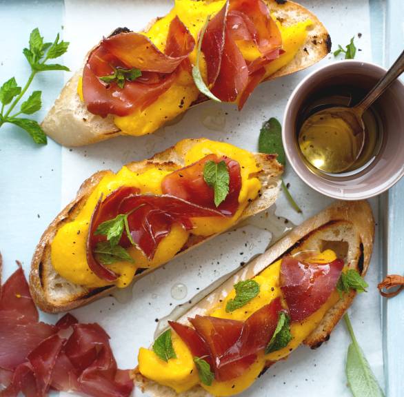 Crostini mit Kürbis und Bresaola belegt auf einem eckigen Teller