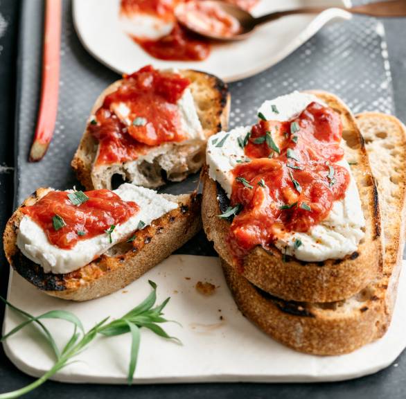 Vier knusprige Crostini mit Ziegenfrischkäse und Rhabarber-Tomaten-Chutney auf einem Vorspeisenteller