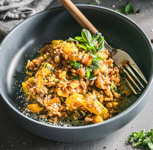 Dinkel-Risotto mit Kürbis und gelber Paprika getoppt von Parmesan in einer Schüssel