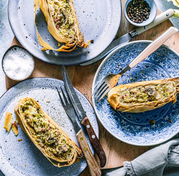 Drei Stücke Gemüsestrudel mit Wirsing, Champignons und Speck auf Tellern angerichtet