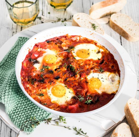 Eier in Tomatensauce all'arrabbiata in einer Pfanne, daneben Ciabattascheiben