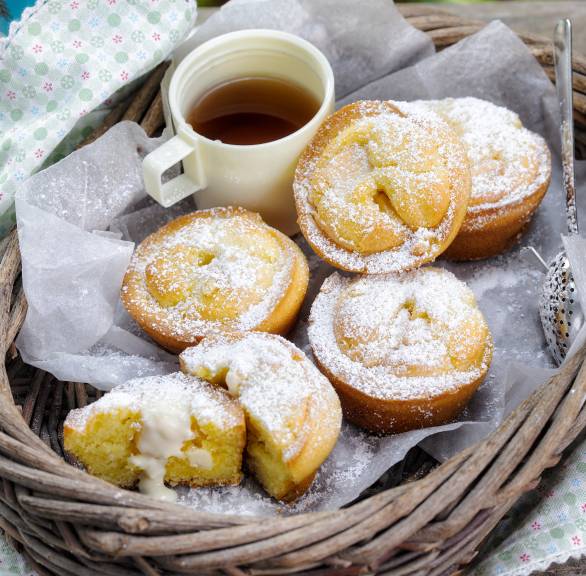 Poffertjes mit Eierlikör und weißem Schokokern in einem Weidenkorb draußen, daneben eine Kanne Tee