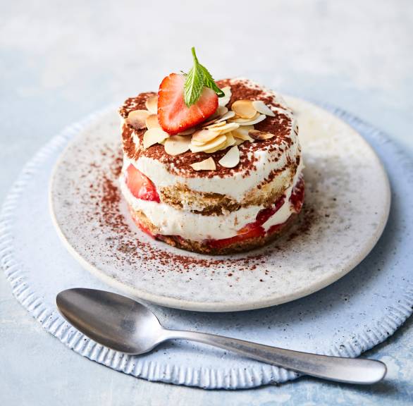 Kreisrund augestochenes Erdbeertiramisu auf einem Teller getoppt von mit Mandelblättchen