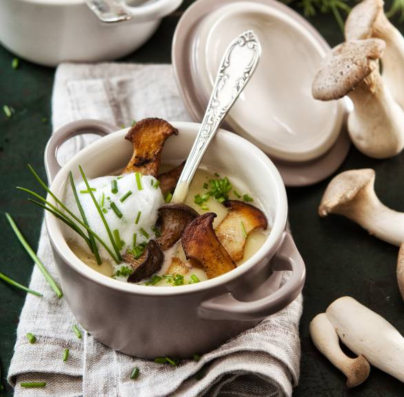 Kartoffelsuppe mit Einlage aus gebratenen Kräuterseitlingen und Topping aus Milchschaum in einem Kochtopf