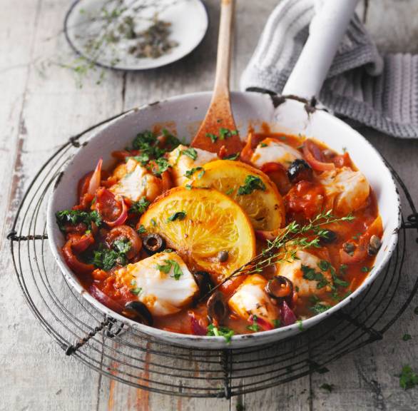 Sizilianische Fischpfanne mit Kapern, Oliven und Orangen auf einem Tisch