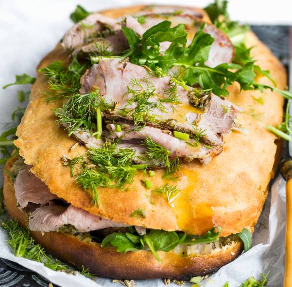 Gefülltes Focaccia mit Schweinebraten und belegt mit frischen Kräutern