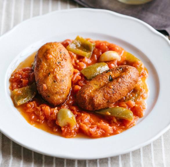 Zwei frittierte Polpette di Ricotta Käsebällchen angerichtet auf Tomaten-Paprika-Sugo