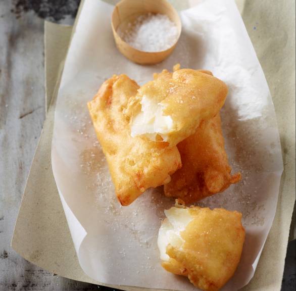 Stücke frittierten Stockfischs auf einem Teller, daneben ein Schälchen Salz