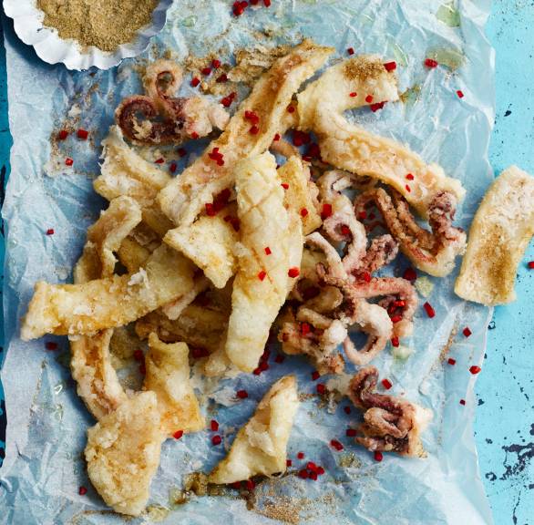 Frittierter Tintenfisch auf einer rechteckigen Platte, daneben Dip