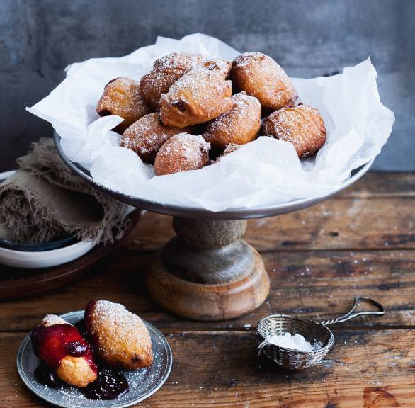 Frittierte Löffel-Krapfen mit Rosinen und Rum angerichtet auf einer Servierplatte