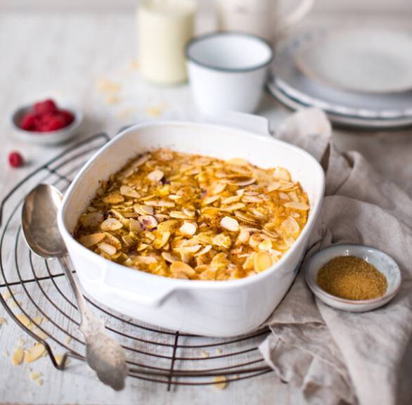 Süßes Risotto mit Himbeeren in einer Auflaufform getoppt mit Mandelblättchen auf einem Kuchengitter