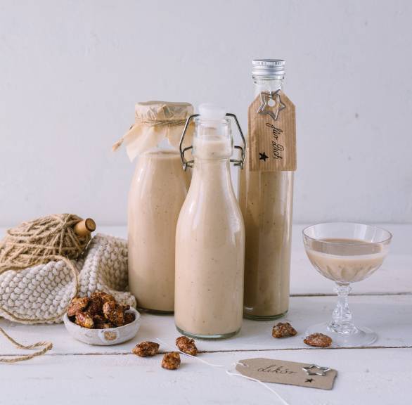 Selbstgemachter Gebrannte-Mandel-Likör in weihnachtlich verpackten Flaschen auf einem Tisch