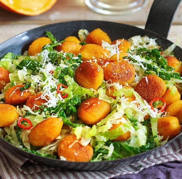 Gebratene Kürbisgnocchi mit Wirsing in einer Pfanne auf einem Tisch