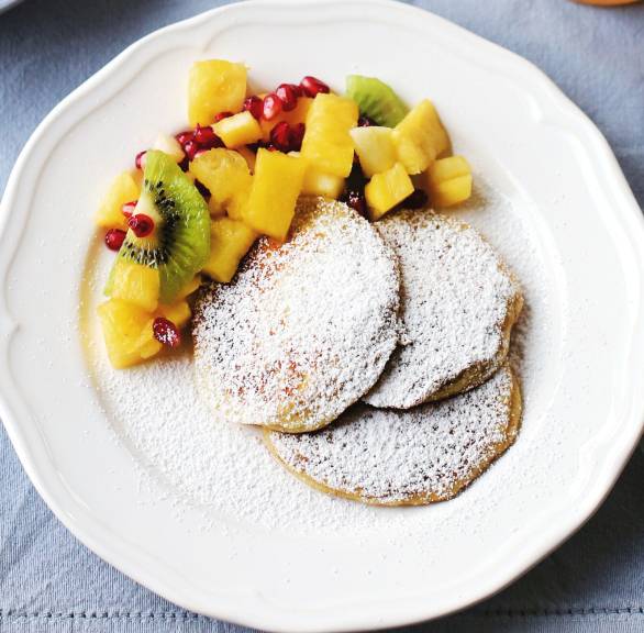 Ricottataler wie Pancakes angerichtet mit Obstsalat auf mehreren Tellern