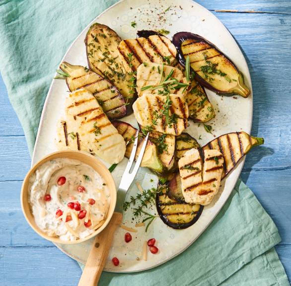 Gegrillte Aubergine und gegrillter Halloumi auf eine Teller, daneben Granatapfel-Quark-Dip in einem Schälchen
