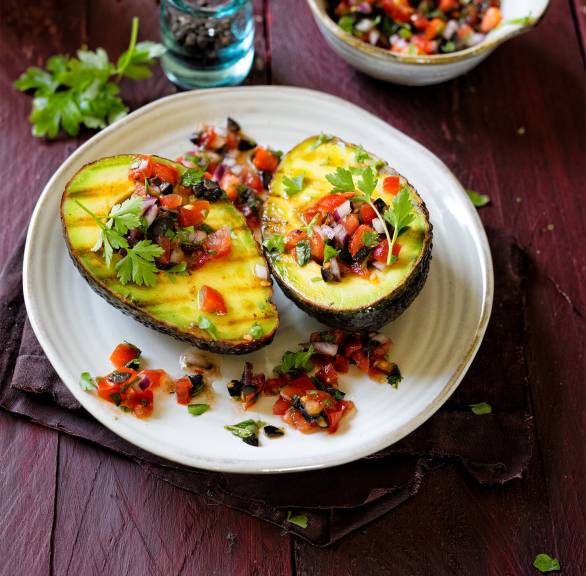 Zwei Gegrillte Avocadohälften mit Tomatensalsa getoppt auf einem Teller