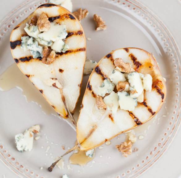 Zwei gegrillte Birnenhälften getoppt mit Gorgonzola und Honig auf einem Teller