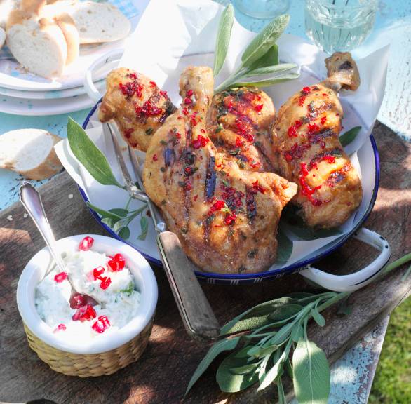 Gegrillte Hähnchenkeulen auf einem Teller, daneben ein Dip in einer Schale
