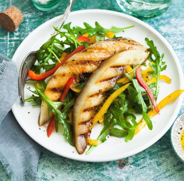 Veganer Rucola-Paprikasalatmit getoppt mit gegrillter Melone angerichtet auf einem Teller