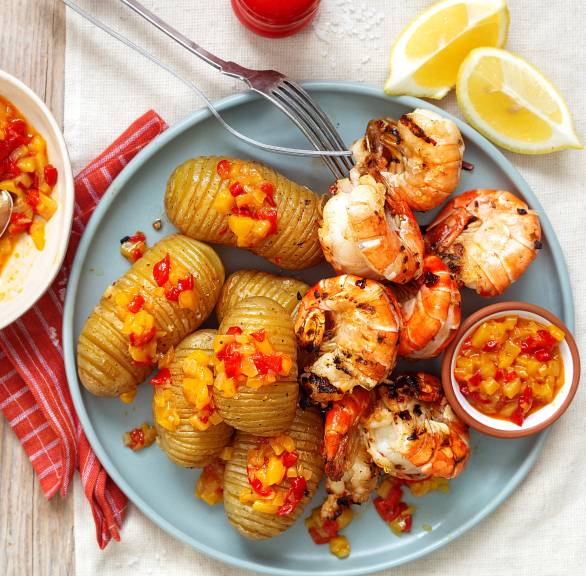 Gegrillte Riesengarnelen und Fächerkartoffeln auf einem Teller getoppt mit Paprika-Mango-Chutney