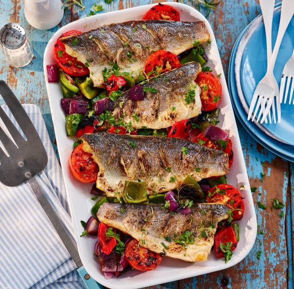 Gegrillter Wolfsbarsch auf Grillgemüse aus Paprika und Tomaten in einer Aluschale