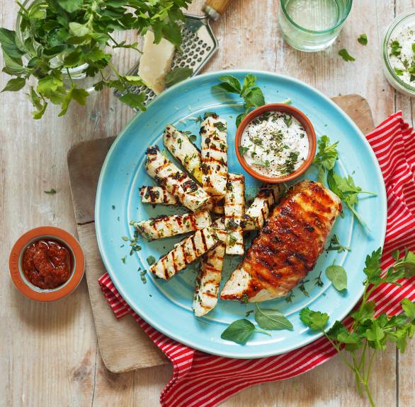 Gegrilltes Hähnchenbrustfilet im Pancettamantel auf einem Teller, daneben gegrillter Knollensellerie und Parmesandip